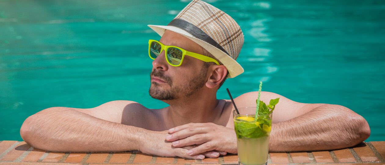man in pool with cocktail