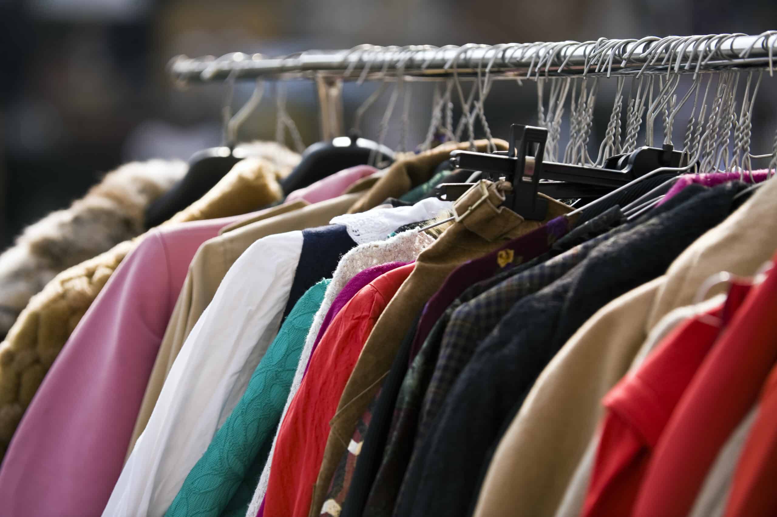 A variety of clothing items hanging on a rack, including shirts, jackets, and coats in different colors and materials.