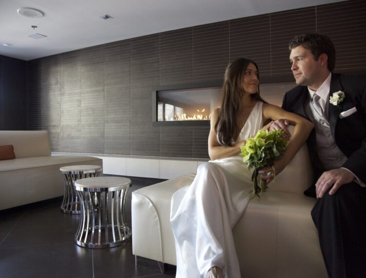bride and groom sitting in lobby near fireplace