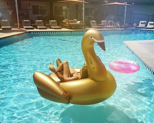 Woman floating on gold swan floatie