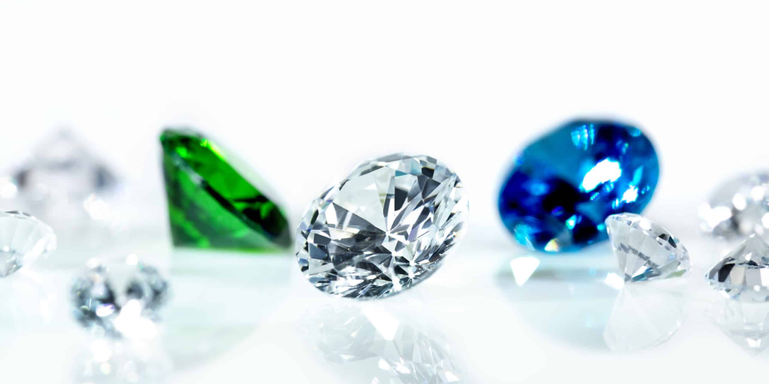 Flawless diamonds, gems, blue sapphire and a green emerald in front of white background