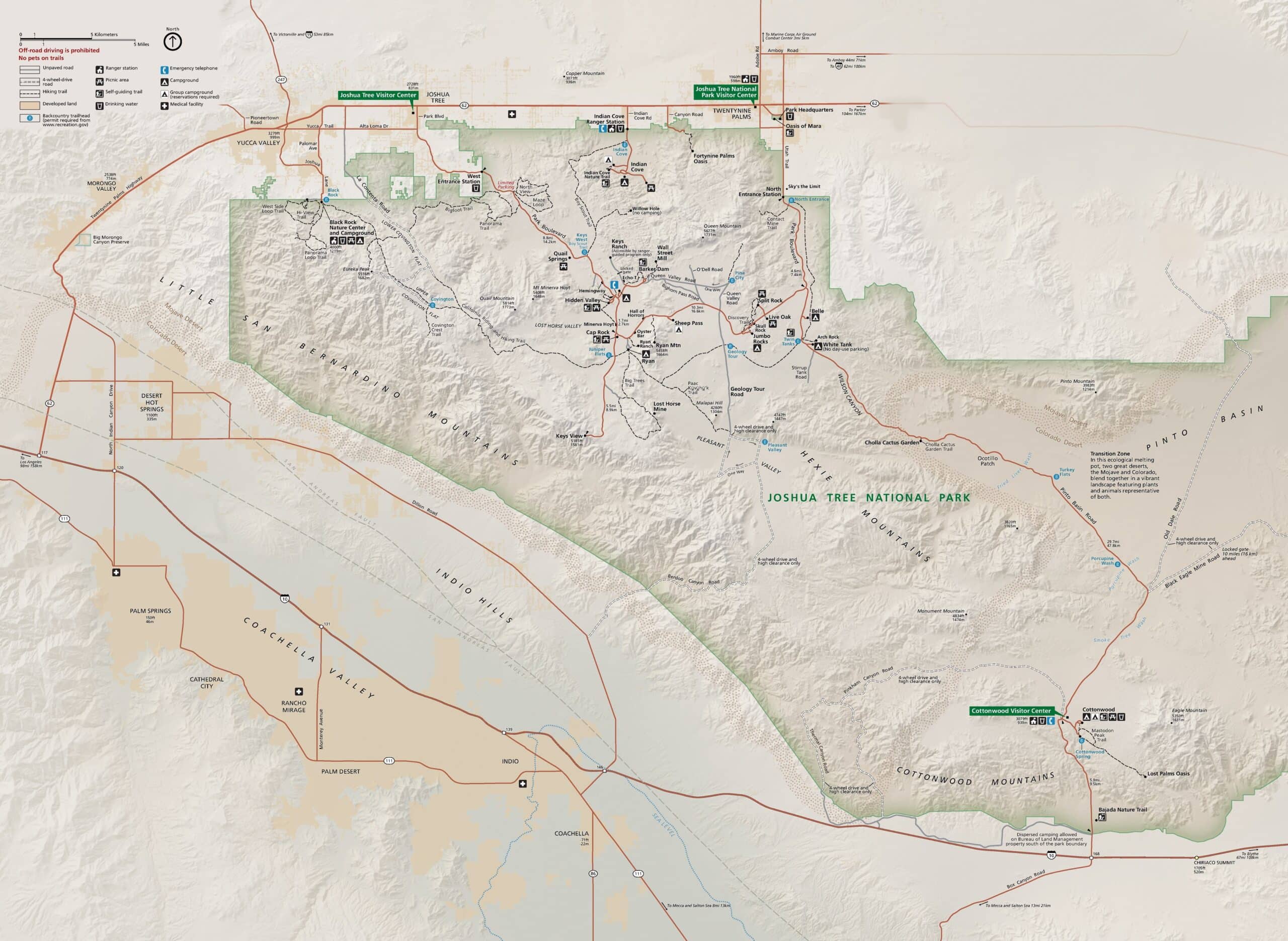 Alt text: A detailed map of Joshua Tree National Park, depicting roads, trails, campgrounds, visitor centers, and points of interest with a legend and topographical features. Surrounding areas like Coachella Valley, Palm Springs, and towns of Twentynine Palms and Joshua Tree are also shown.