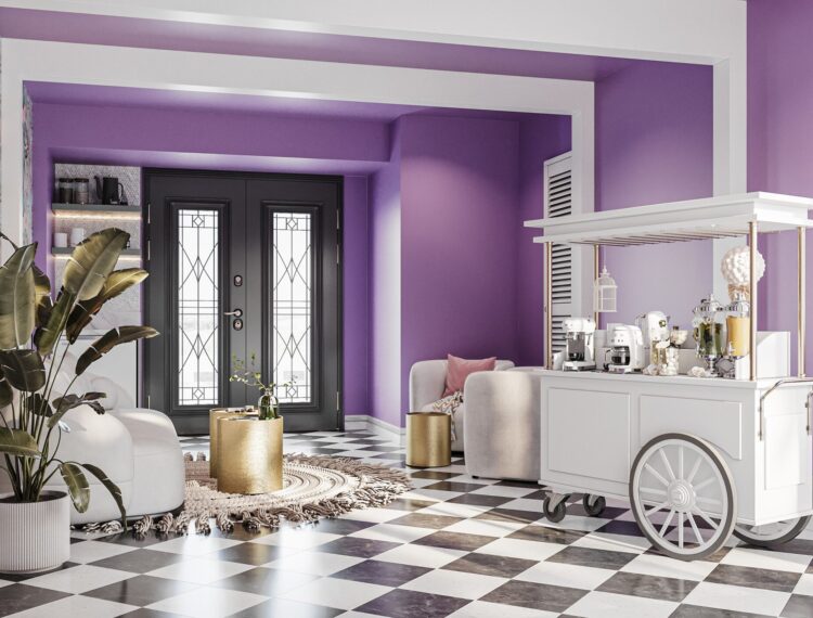 A modern living room with purple walls, a black and white checkerboard floor, and a decorative coffee cart. The room features a large, leafy indoor plant, a round gold-colored side table, a gray sofa with pink cushions, and a patterned area rug. The space is well-lit with natural light coming from the black-framed double doors with glass panels.