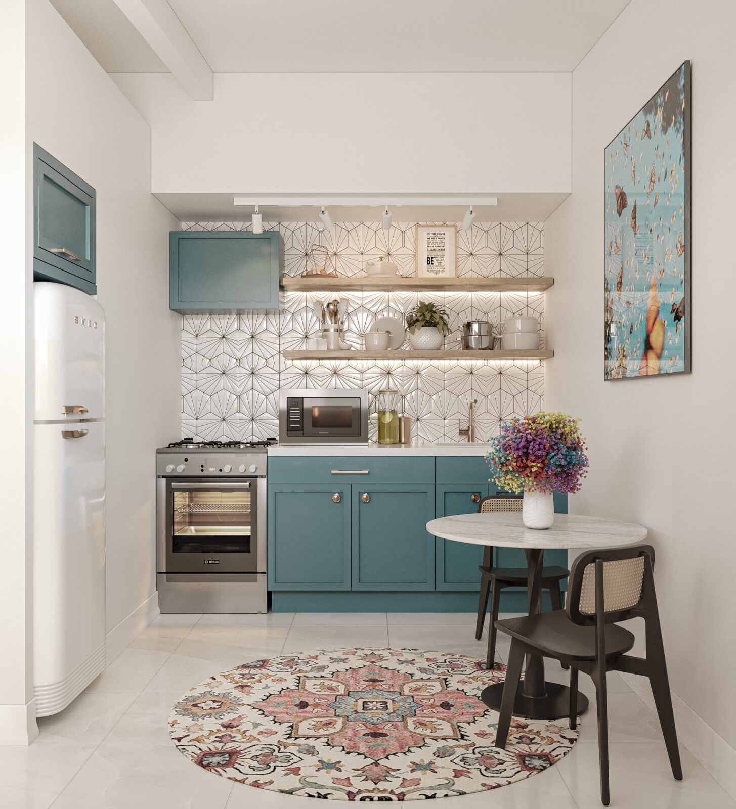 A modern kitchen with teal cabinetry, white countertops, geometric backsplash tiles, and stainless steel appliances. There's a round dining table with two chairs, a colorful area rug on the floor, and decorative items including a vase of flowers and wall art.